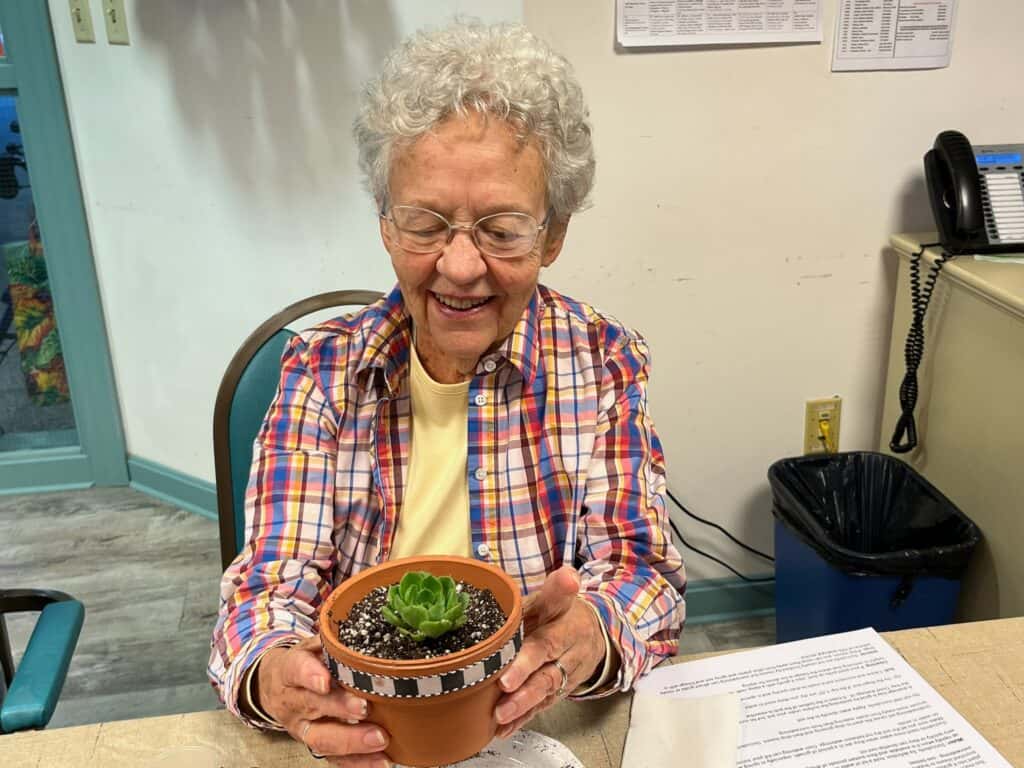 Harvest Hill Resident  displays her beautiful result of our potting up succulents activity.